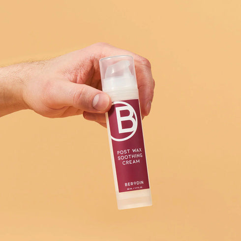 A hand holding a Berodin soothing cream bottle